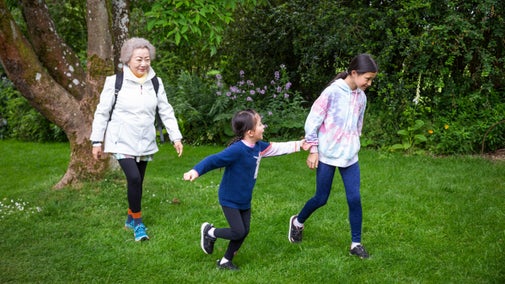 Visitors walking on grass with vibrant trees in the background enjoying a late spring visit to Hidcote, Gloucestershire
